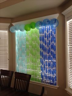 balloons and streamers are hanging from the window in this dining room decorated for a party