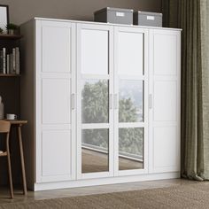 a large white cabinet with glass doors in a living room next to a table and chair