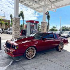 a red car parked in front of a gas station