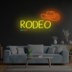 a neon sign that reads welcome to the rodeo on a wall above a couch in a living room