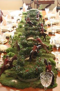 a long table is decorated with moss and figurines