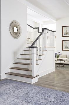 a living room filled with furniture and a stair case in front of a white wall