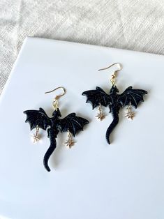 Black dragons made from clay, each dragon with two 18k gold plated north star charms  My earrings  are handmade with polymer clay, an extremely light weight and versatile material. Each individual piece is handcrafted with care and attention, no two are alike. There may be slight variations in colors or shape and potential imperfections. Choose your hardware made from gold* or silver and choose between ball posts, lever back huggie hoops, hooks or hoops. Hardware used may vary from photos.  *Gol Dragon Clay, Black Dragons, Fantasy Earrings, Celestial Earrings, Dragon Earrings, Knoxville Tennessee, Disney Dolls, Black Dragon, North Star