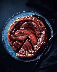 a blue plate topped with sliced sausages on top of a black table next to a knife