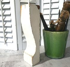 a green vase sitting on top of a cement block next to a white door with shutters