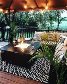 an outdoor living area with couches, tables and lights on the patio roof over looking water