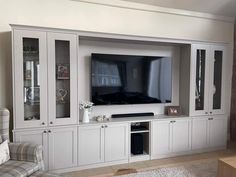 a living room with white furniture and a flat screen tv mounted on the side of it