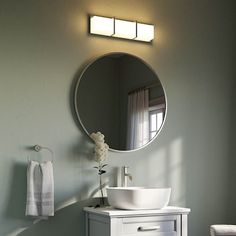 a white sink sitting under a round mirror