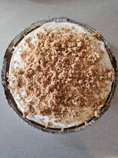 a pie with white frosting and crumbs on top sitting on a table