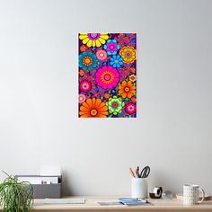 an abstract painting of colorful flowers on a white wall above a wooden desk with office supplies