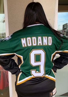 the back of a woman wearing a green and white hockey jersey that reads modand 9