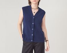 "Vintage Dark Blue Wool Sweater Vest size M | V-Neck Sweater Vest with Buttons Closure Composition: 100% wool Measurements while lying flat: Armpit to armpit: 45 cm | 17.7\" Length: 60 cm | 23.6\" Shoulder to shoulder: 38 cm | 15\" Condition: excellent.  This dark blue wool sweater vest is photographed on a size S model (chest: 88 cm|35\", waist: 68|26\" cm, hips: 88 cm|35\", height: 1,68 m|5.5ft) The tuxedo style, black wool pants in the pictures are made by us, they are 100% wool and you can order your custom size here: https://etsy.me/3TYqYYJ Our shop is dedicated to curated vintage and handmade clothing, fine fabrics only. Check out our vintage wool selection for more similar wool essentials: https://etsy.me/3PXiFti We offer discounts for multiple purchases: Buy any 2 items in shop and Blue Sweater Vest For Spring Workwear, V-neck Wool Tops For Workwear, Blue Wool Cardigan For Layering, Blue Cashmere Tops For Work, Wool V-neck Workwear Tops, Classic Blue V-neck Sweater For Work, Sweater Vest With Buttons, Blue Sweater Vest For Workwear, Spring Season, V-neck Cashmere Sweater Vest For Work