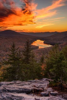 the sun is setting over some mountains and trees