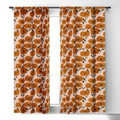 an orange floral curtain hanging on a window