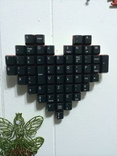 a heart made out of black keys on a wall next to a potted plant