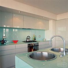 a modern kitchen with stainless steel sink and green counter tops, along with white cabinets