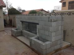 an outdoor fireplace built into the side of a house with cement blocks around it and brick walls