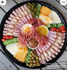 a platter filled with meats, cheese and vegetables