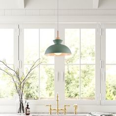 a kitchen with an island sink and green pendant light hanging over it's windows