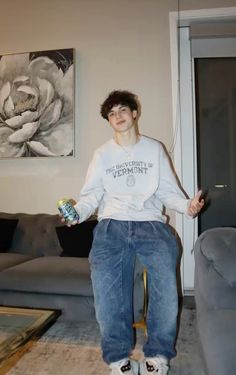 a young man sitting on top of a couch holding a can in his right hand