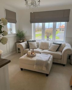 a living room filled with furniture and a chandelier hanging from the ceiling next to a window