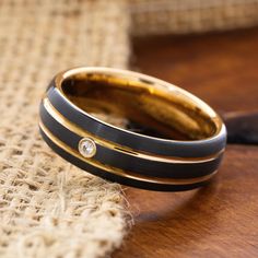 two black and gold wedding bands sitting on top of each other