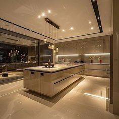 a large kitchen with an island in the middle and lights hanging from it's ceiling