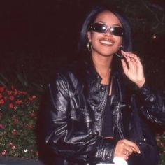 a woman in black leather jacket and sunglasses talking on cell phone while sitting outside at night