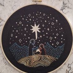 a cross - stitch christmas scene with a nativity scene in the middle and stars above it