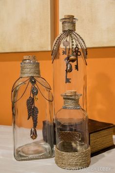 two glass bottles sitting on top of a table next to an open book with charms in them