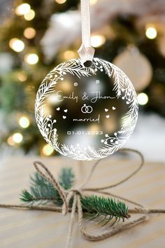 a christmas ornament on top of a present box with a tree in the background