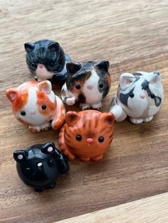 five small ceramic cats sitting on top of a wooden table