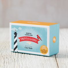 a box of trivia game sitting on top of a white wooden table next to a black and white lighthouse