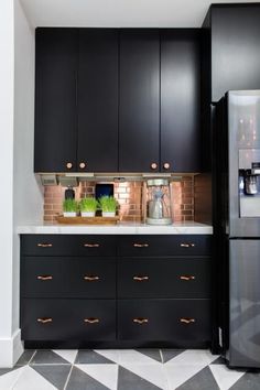 a kitchen with black cabinets and white tile flooring on the walls, along with a stainless steel refrigerator