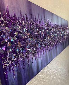 a purple painting with lots of crystals hanging on it's wall in front of a white wall