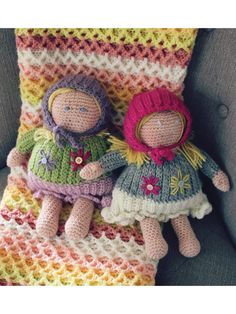 two crocheted dolls sitting on top of a blanket