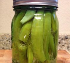 pickled green beans in a mason jar on a cutting board