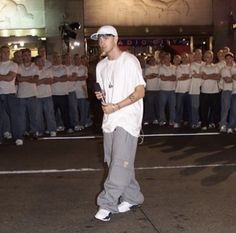 a man standing in front of a group of people wearing white shirts and grey pants