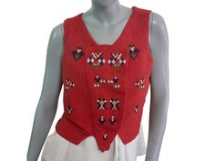 This unique 1990s vintage burnt orange wool vest features embroidered symbols on the front and back, an eight hook-and-eye closure in the front, and a peplum hemline in the back. Condition: Near Mint (Like New ... Professionally Cleaned ... soft and supple, with no stains, tears, wear spots, or weaknesses in the seams)  Size 12 US, 16 UK Bust = 40 inches (101.6cm) Waist = 37 inches (93.98cm) Hemline = 34 inches (86.36cm) Vest Length = 19.5 inches (49.53cm) Material: Wool Traditional Fitted Fall Vest, Traditional Fitted Vest For Fall, Vintage Embroidered Vest For Festivals, Fitted Vintage Vest With Embroidery, Vintage Fitted Embroidered Vest, Vintage Embroidered Fitted Vest, Vintage Fitted Multicolor Vest, Vintage Embroidered Sleeveless Vest, Vintage Sleeveless Vest With Button Closure