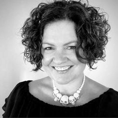 black and white photograph of a smiling woman wearing a necklace with skulls on the front