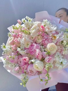 a woman holding a bouquet of pink and white flowers