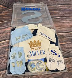 baby shower gift box with personalized items in clear plastic container on wooden table top