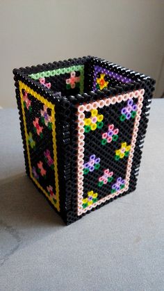 a small square beaded object sitting on top of a white table next to a wall