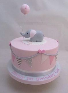 a pink birthday cake with an elephant on top