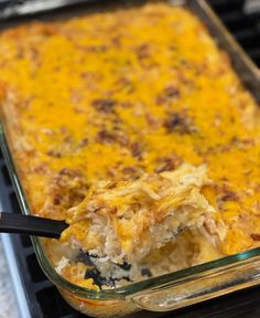 a casserole dish with meat and cheese in it being lifted from the oven by a spatula