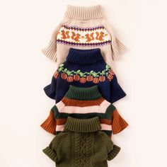 four sweaters are stacked on top of each other, all in different colors and patterns