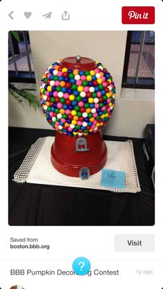 a gummy ball machine sitting on top of a black tablecloth covered floor next to a window