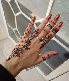 a woman's hand with hennap tattoos on her fingers and wrist,