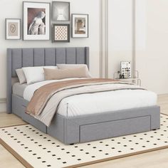 a bed sitting on top of a wooden floor next to a wall with pictures above it