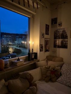 two teddy bears sitting on a couch in front of a window with the city outside